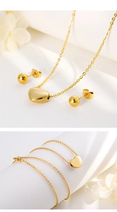 Golden heart pendant necklace and ball stud earrings set displayed with dried flowers