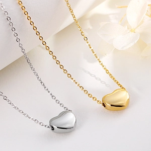 Elegant stainless steel heart pendant necklaces in gold and silver on marble background