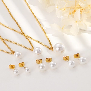 Ensemble élégant de colliers et boucles d'oreilles en perles dorées sur surface blanche décorée