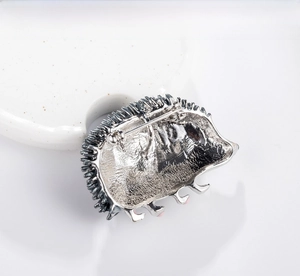 Close-up of hedgehog brooch back showing metal texture and safety pin clasp mechanism