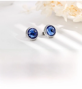 Macro detail of round blue zircon stud earrings with silver-tone polished finish