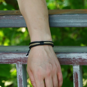 Vintage multilayer black leather and beige woven bracelet on male wrist outdoors