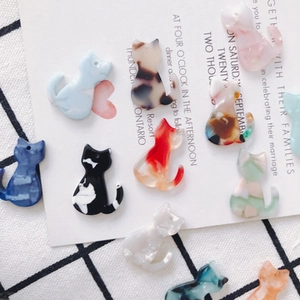 Close-up of cat-shaped acrylic charms in various marble patterns and pearlescent colors