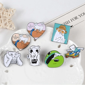 Detailed shot of funny cartoon enamel pins with cat designs on a white ceramic tray