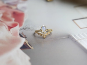 Dettaglio anello a corona dorato con opale a forma di pera e accenti in diamante lucido