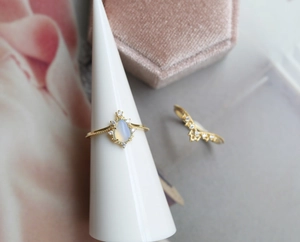 Dettaglio di un anello a corona in oro con opale a goccia e piccoli diamanti brillanti