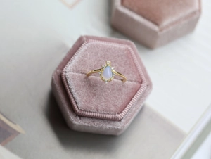 Dettaglio dell'anello a corona dorata con una pietra d'opale bianco a forma di pera