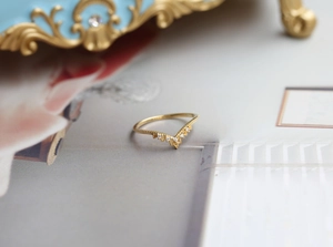Vista macro di un anello a V dorato con delicato design a pizzo e piccoli diamanti