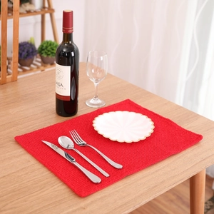 Elegant red woven Christmas placemat on a wooden table with formal dining setup