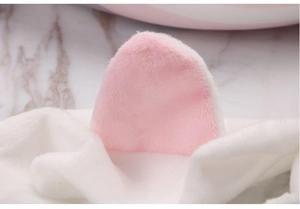 Close-up of soft pink and white plush cat ear headband on marble surface