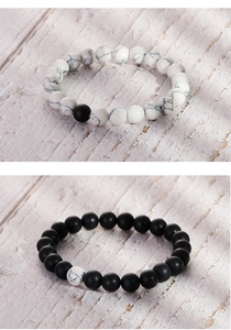 Detailed view of matte black and white marble bead bracelets on a natural textured background