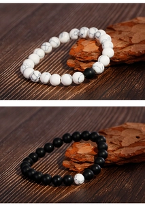 Detail of matte black agate and white turquoise beaded bracelets on wooden texture