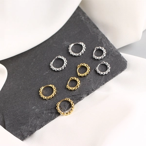 Detailed view of silver and gold beaded hoop earrings on a dark stone texture