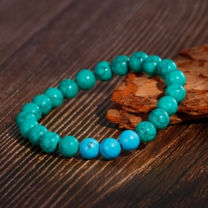 Fashion turquoise beaded bracelet with blue round stones on a natural wood base