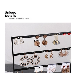 Detail view of various fashion earrings including pearls and fur balls on a black metal rack