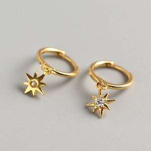 Macro shot of gold octagonal star earring with sparkling center zircon crystal detail