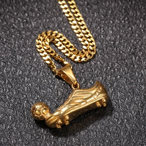 Macro detail of gold-plated soccer shoe and ball pendant on black textured leather