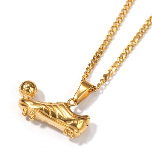Macro detail of gold-plated soccer shoe pendant with cleats and football textures