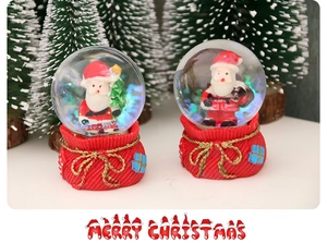 Detailed view of resin Christmas snow globes featuring Santa Claus inside red gift bags