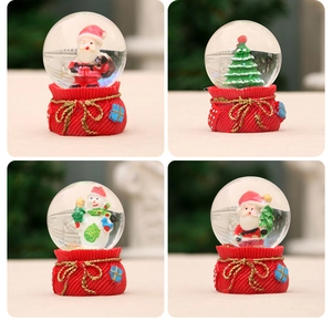 Close-up of four Christmas glass globes with Santa, snowman and tree on red bases