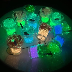 Luminous miniature resin drink charms with glowing beads and black straws in dark scene
