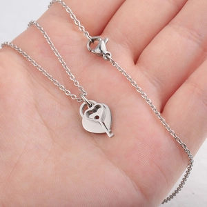 Silver stainless steel heart lock and key pendant necklace held in hand for close-up view