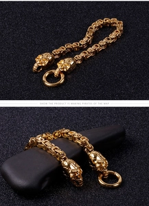 Detailed shot of golden skull bracelet with square weave chain on dark textured background