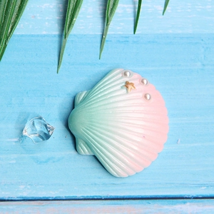 Macro detail of gradient resin shell with pearl and starfish on blue wood surface