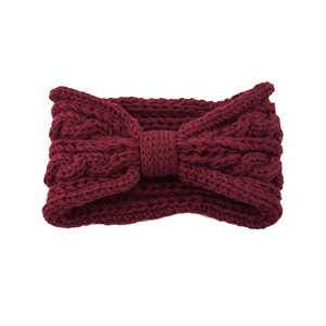 Close-up of wine red knitted headband with chunky cable knit texture and central bow knot