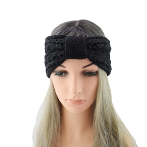 Detail view of the black knitted headband with a decorative twist knot on a display model