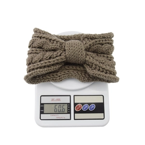 Brown knitted bow headband shown on a digital scale weighing 60.6 grams for detail