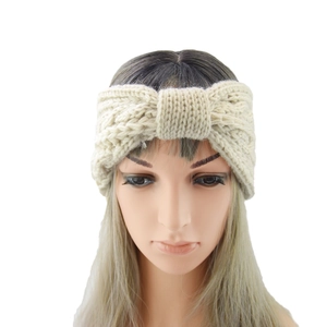 Close-up of beige chunky cable-knit headband with center bow design on a model head