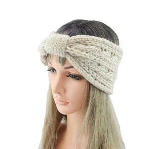 Detail of cable knit beige headband featuring thick wool texture and twisted knot design