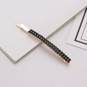 Macro detail of double-row dark green rhinestones on a rose gold hair clip