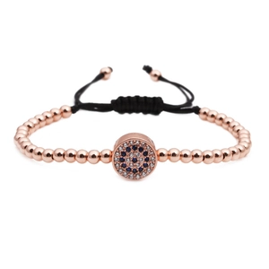 Rose gold beaded woven bracelet with blue zircon evil eye charm on white background