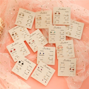 Flat lay of multiple earring sets on pink tulle with daily labels from Monday to Saturday