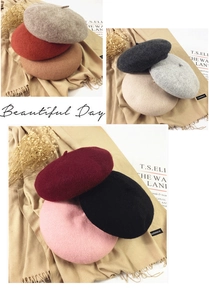 Close-up of wool beret hats in various colors with textured fabric and autumn props