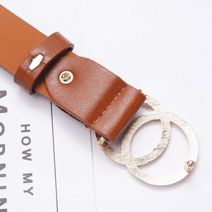 Macro detail of brown leather belt featuring a classic golden double circle interlocking buckle