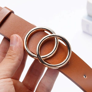 Detail of a brown leather belt with a polished gold double ring buckle held by hand