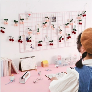 Pink grid wall organizer with red and pink plush cherry ball garlands for room decor
