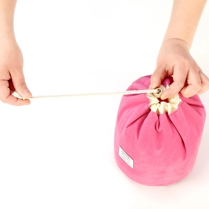 Beauty case in velluto rosa con coulisse mostrato durante la chiusura del sacchetto