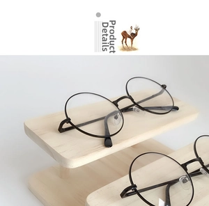 Close-up of retro black round glasses on a solid wood minimalist display stand