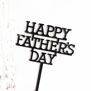 Close-up of black acrylic Happy Father's Day cake topper with hollow lettering design