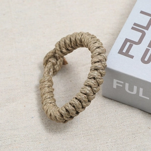 Vue macro d'un bracelet en corde de chanvre marron tressé à la main sur fond de lin