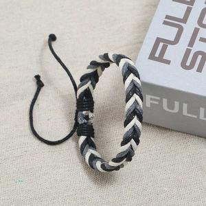 Detail of hand-woven cord bracelet in black, white, and gray with adjustable drawstring