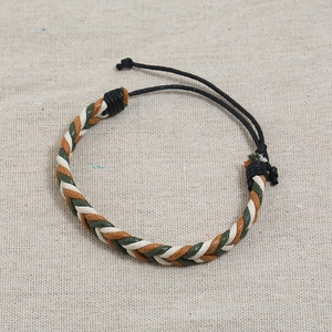 Handmade braided wax rope bracelet for couples in brown, white, and green on fabric