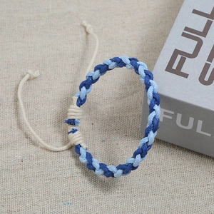 Adjustable woven rope bracelet in blue and beige tones on a textured linen background