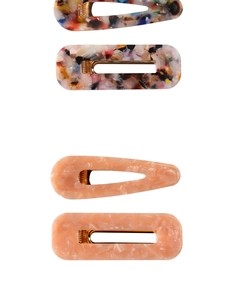 Close-up of marble pattern and peach resin hair clips with golden metal clamps