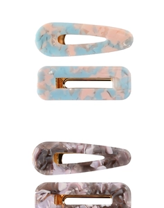 Detail of four acetate marble texture hair clips with gold metal base in varied shapes