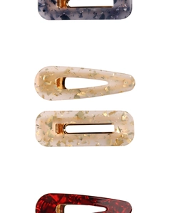 Detail of four acetate hair clips with marble patterns and gold flakes on metal clips